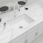 White quartz composite undermount single bowl kitchen sink installed in a marble countertop