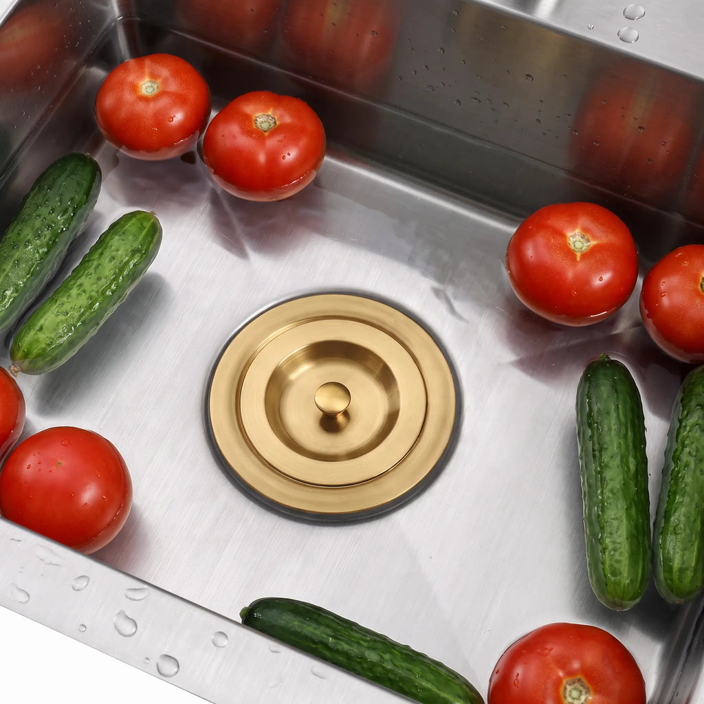 Gold sink stopper installed in a stainless steel kitchen sink