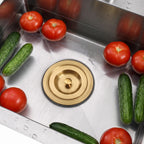 Gold sink stopper installed in a stainless steel kitchen sink