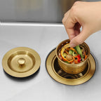 Removable basket strainer holding food scraps in a gold kitchen sink drain