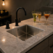 Small stainless steel bar sink with black faucet on a kitchen island