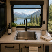 Stainless steel RV sink in a compact camper kitchen with scenic mountain view